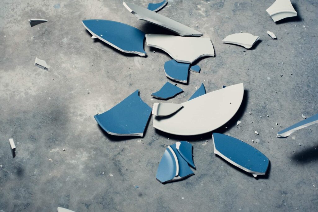A shattered blue plate on a cement floor