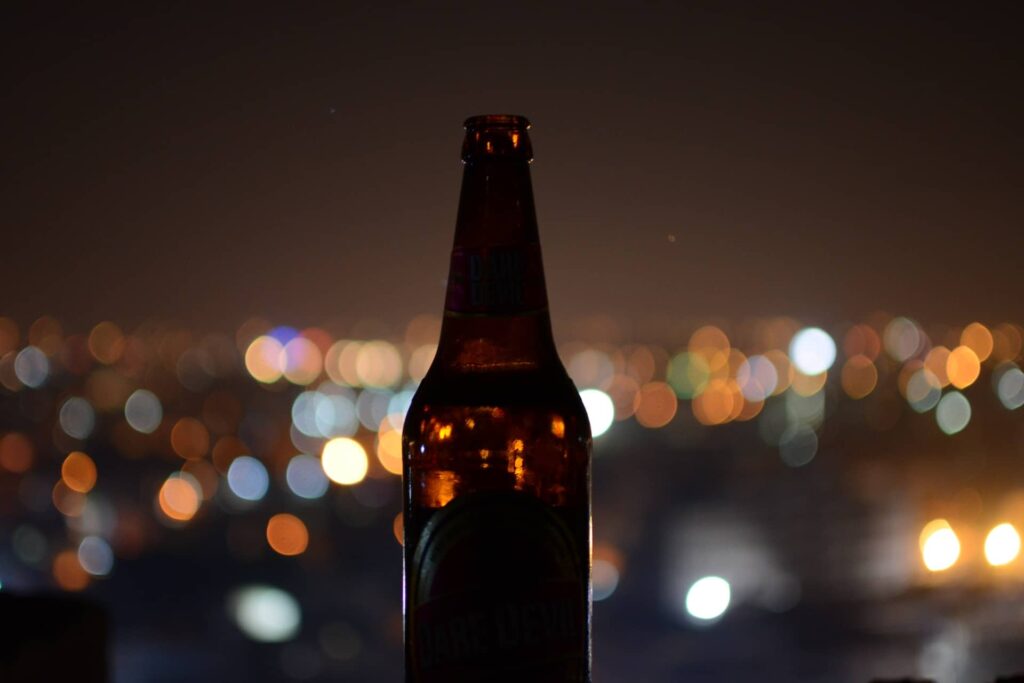An empty bottle against the blurry lights of a city skyline