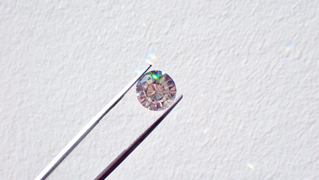 A gemstone held between a pair of pliers