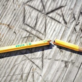 A broken pencil on a wooden table